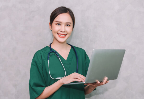 Portrait of beautiful asian woman doctor healthcare worker using laptop isolated on grey background